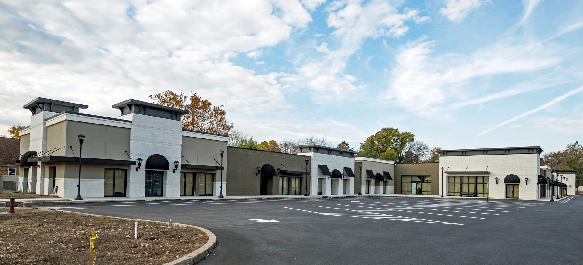 A finished multi-tenant retail center with striped parking lot and landscaping, ready for occupancy
